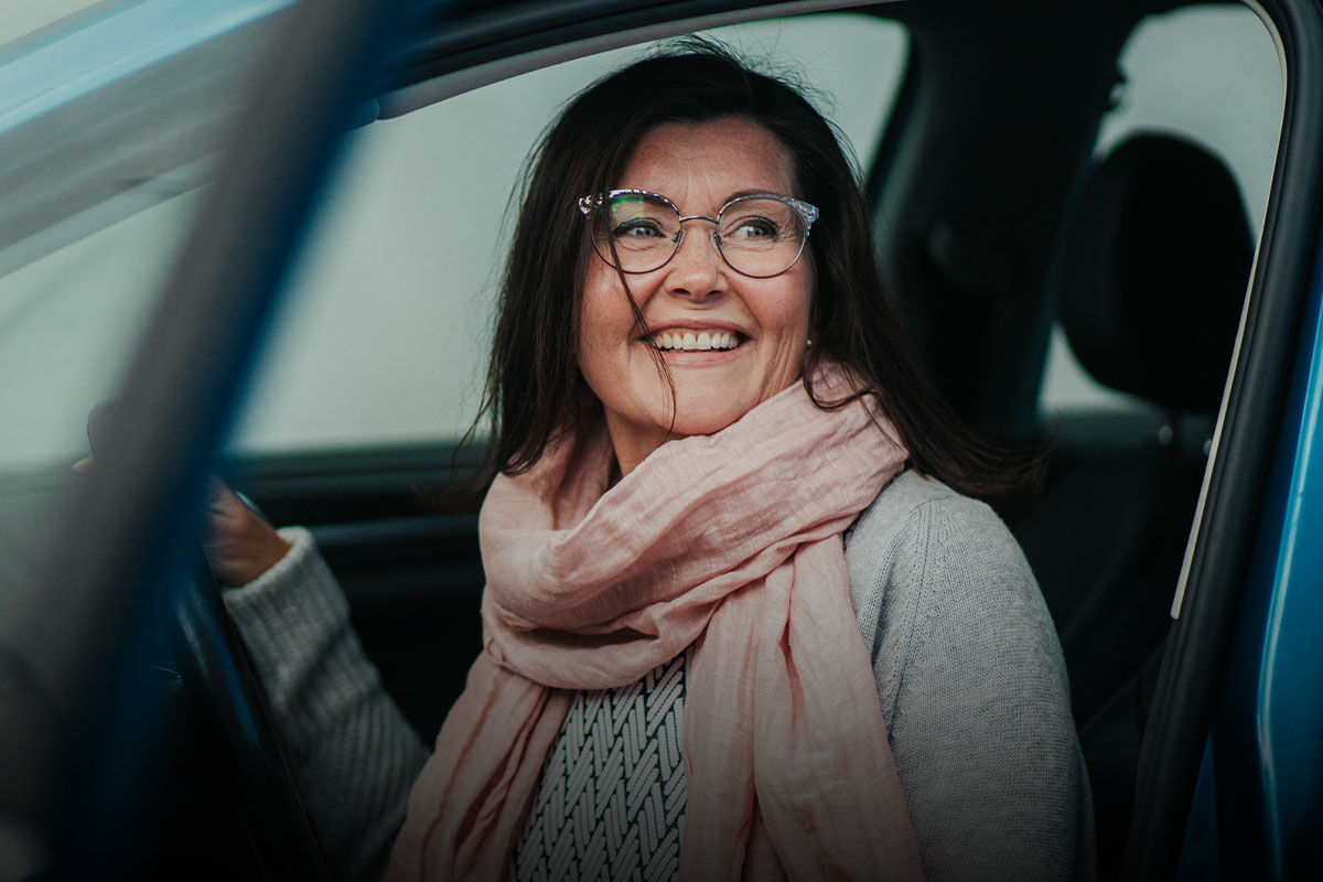 Hymyilevä nainen autonratissa